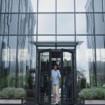 Upset manager standing at office door. Annoyed employees leaving shaming woman.