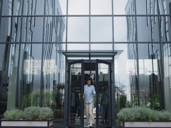Upset manager standing at office door. Annoyed employees leaving shaming woman.